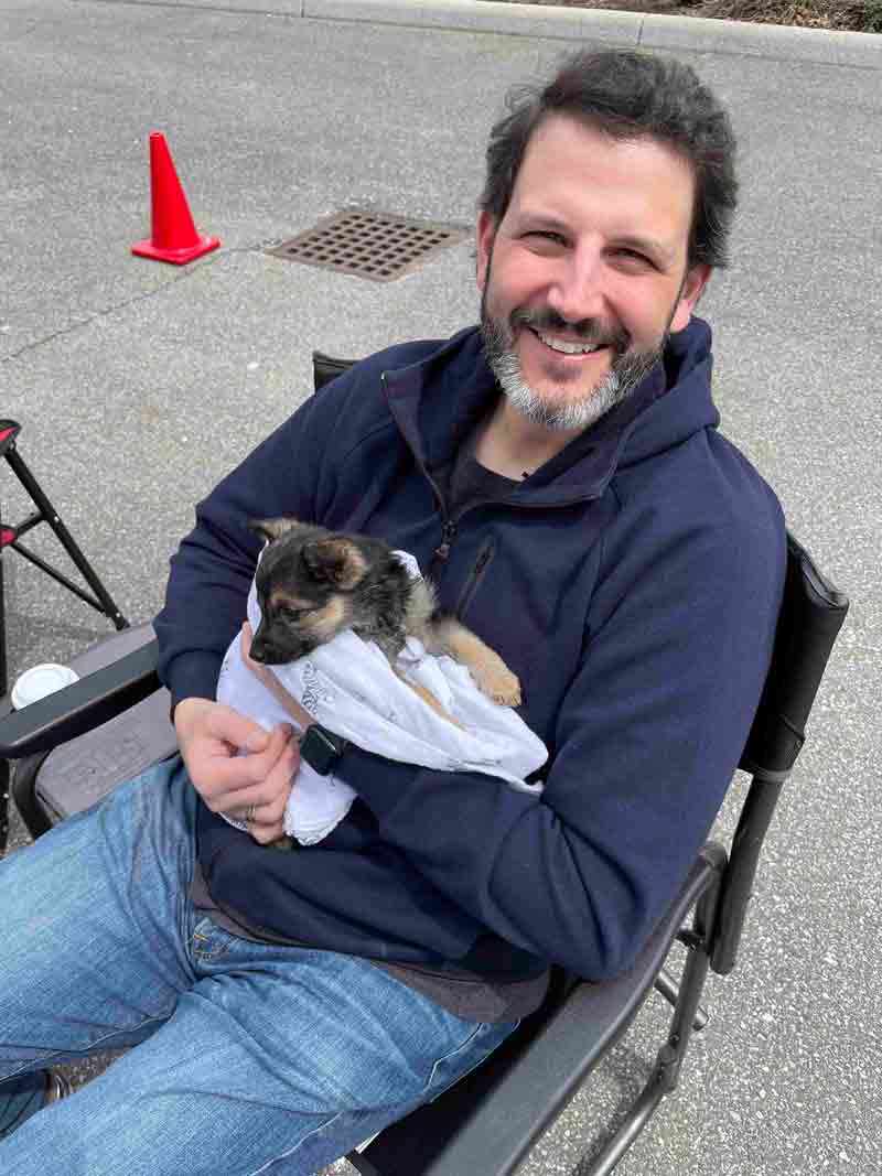 Image of Rick holding an adorable puppy. 